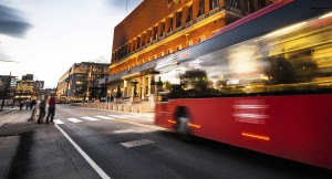 Uskarpt bilde av rød buss i fart foran Oslo Rådhus
